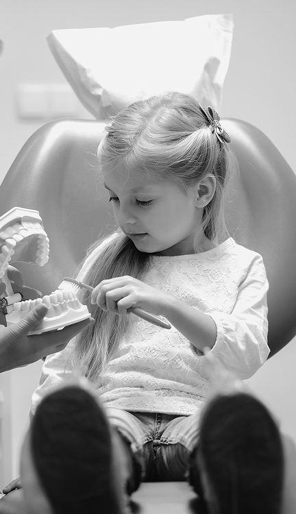 Young patient in the dental chair with a toothbrush and dental model